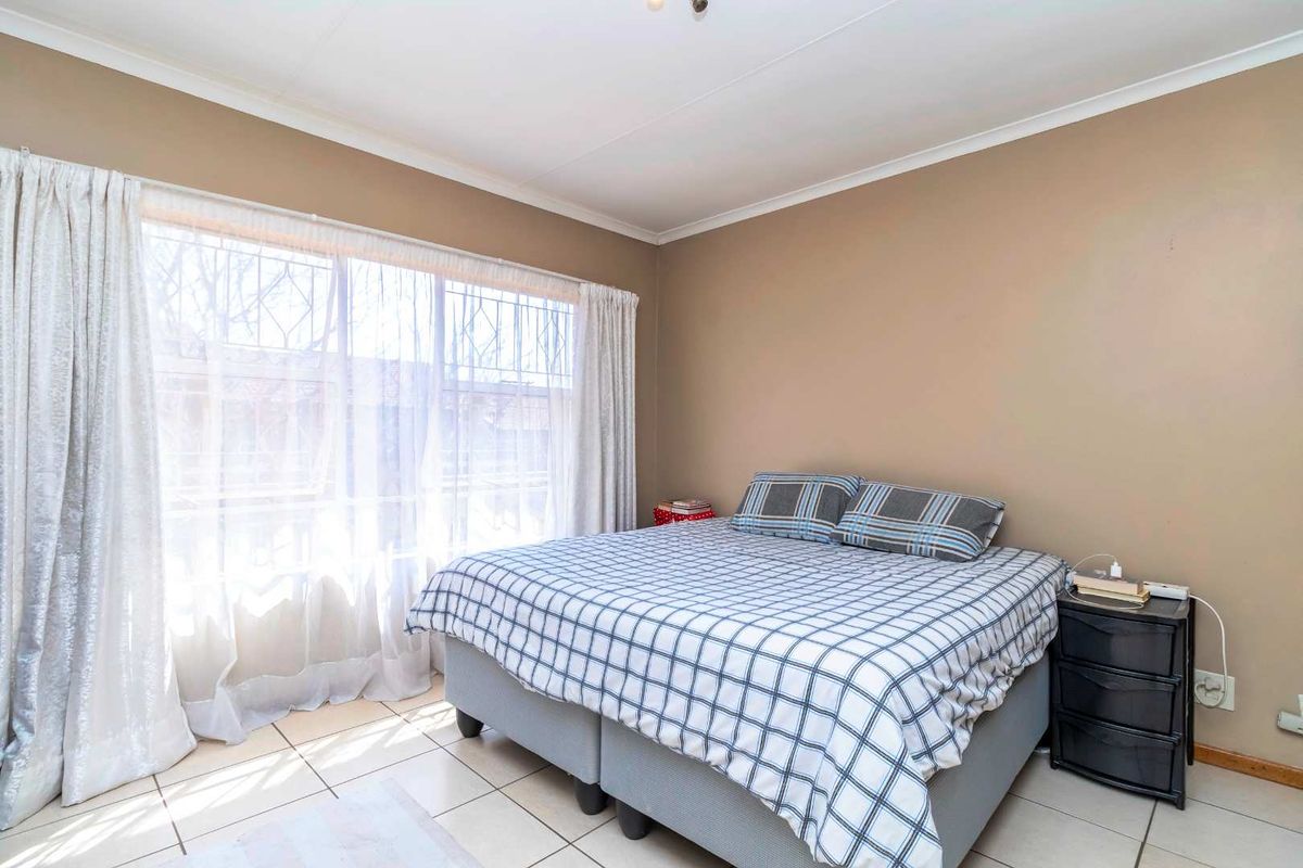 A bedroom featuring tiled flooring and a large window with curtain tracks, providing natural light.