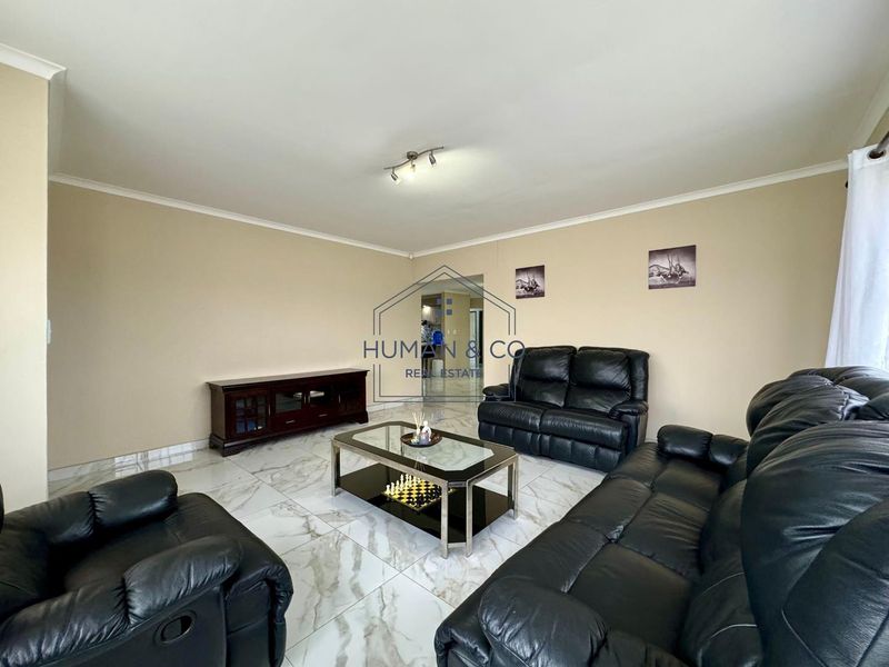A spacious living room featuring polished marble-look floor tiles, neutral wall tones, and modern ceiling lighting, providing a clean and bright foundation for living.
