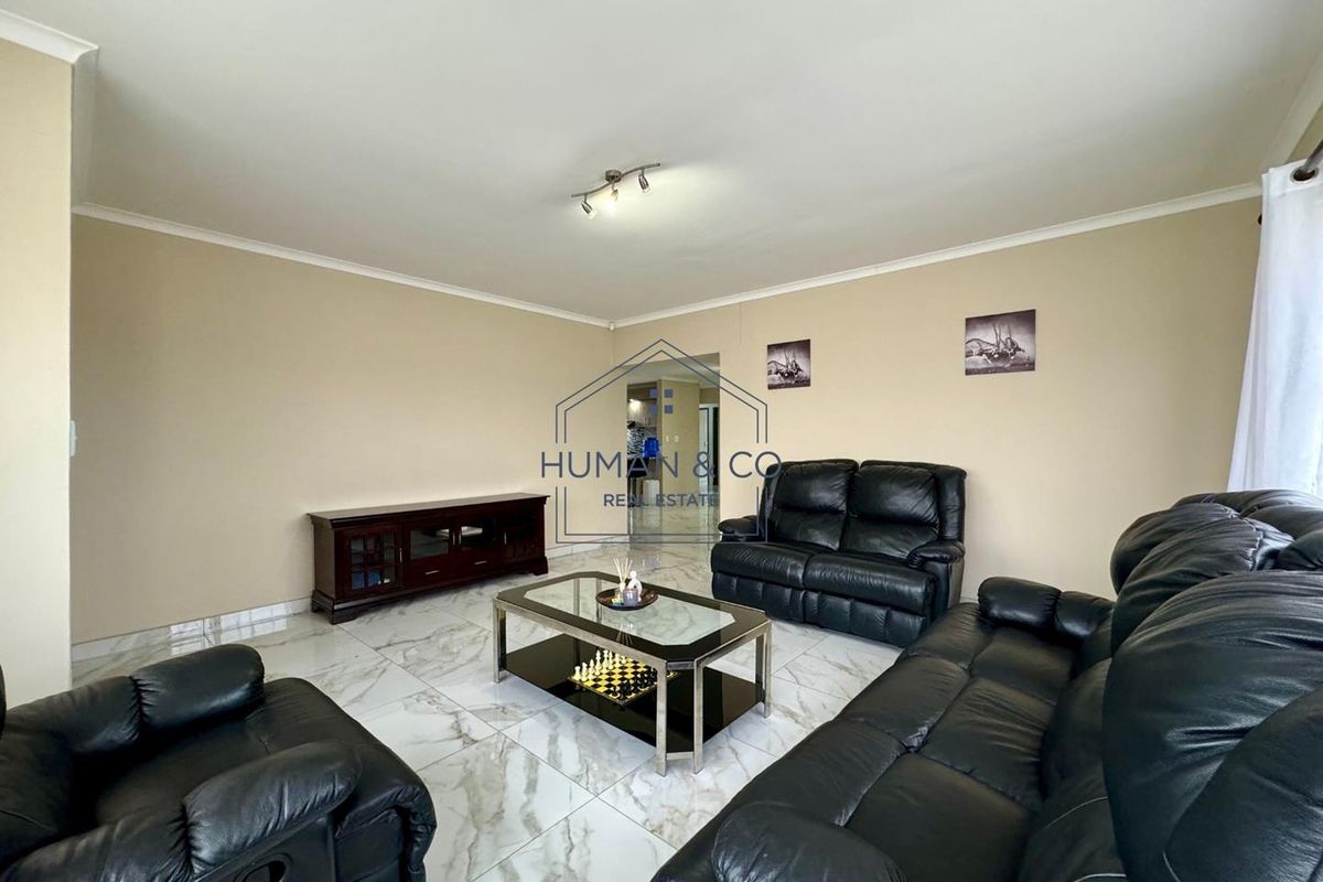 A spacious living room featuring polished marble-look floor tiles, neutral wall tones, and modern ceiling lighting, providing a clean and bright foundation for living.