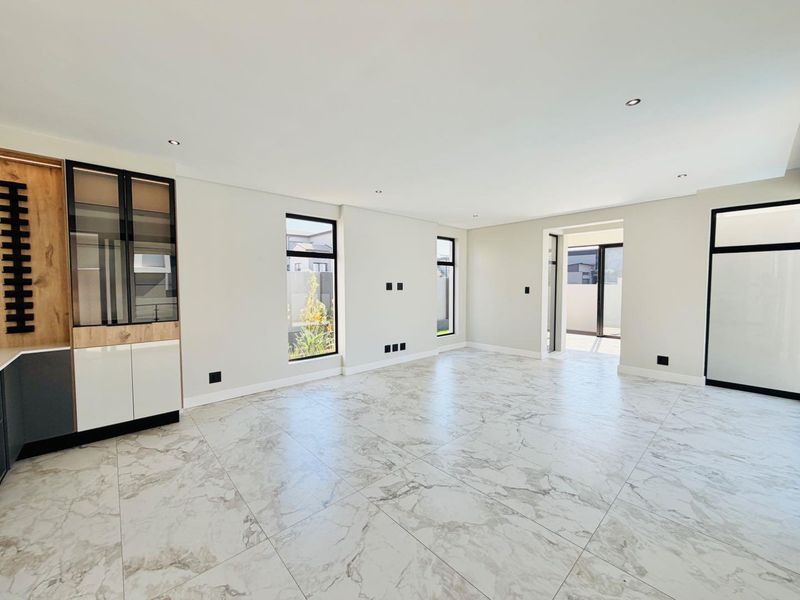Spacious living area featuring modern marble-look floor tiles, recessed lighting, and sleek built-in cabinetry with large windows providing natural light.
