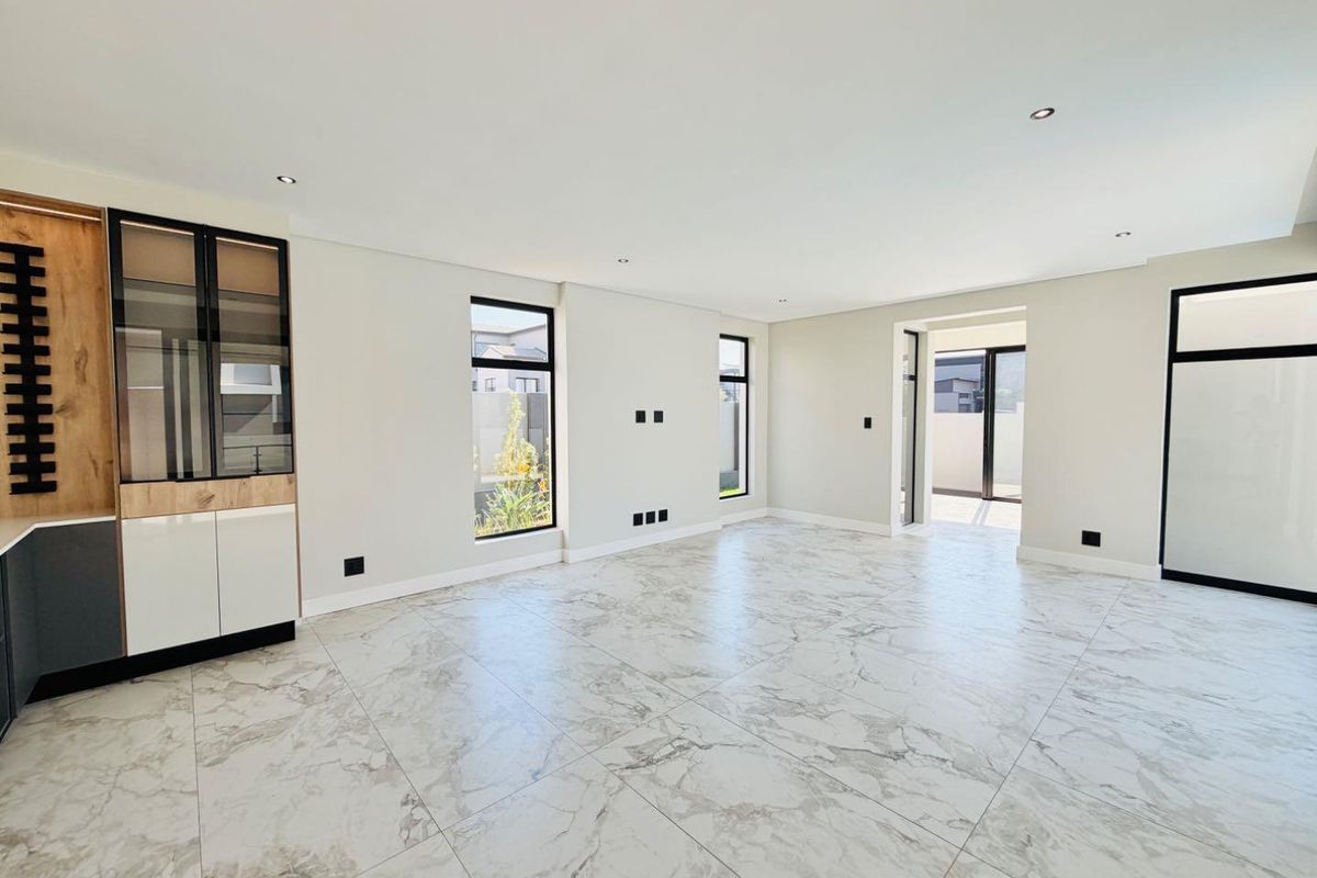 Spacious living area featuring modern marble-look floor tiles, recessed lighting, and sleek built-in cabinetry with large windows providing natural light.