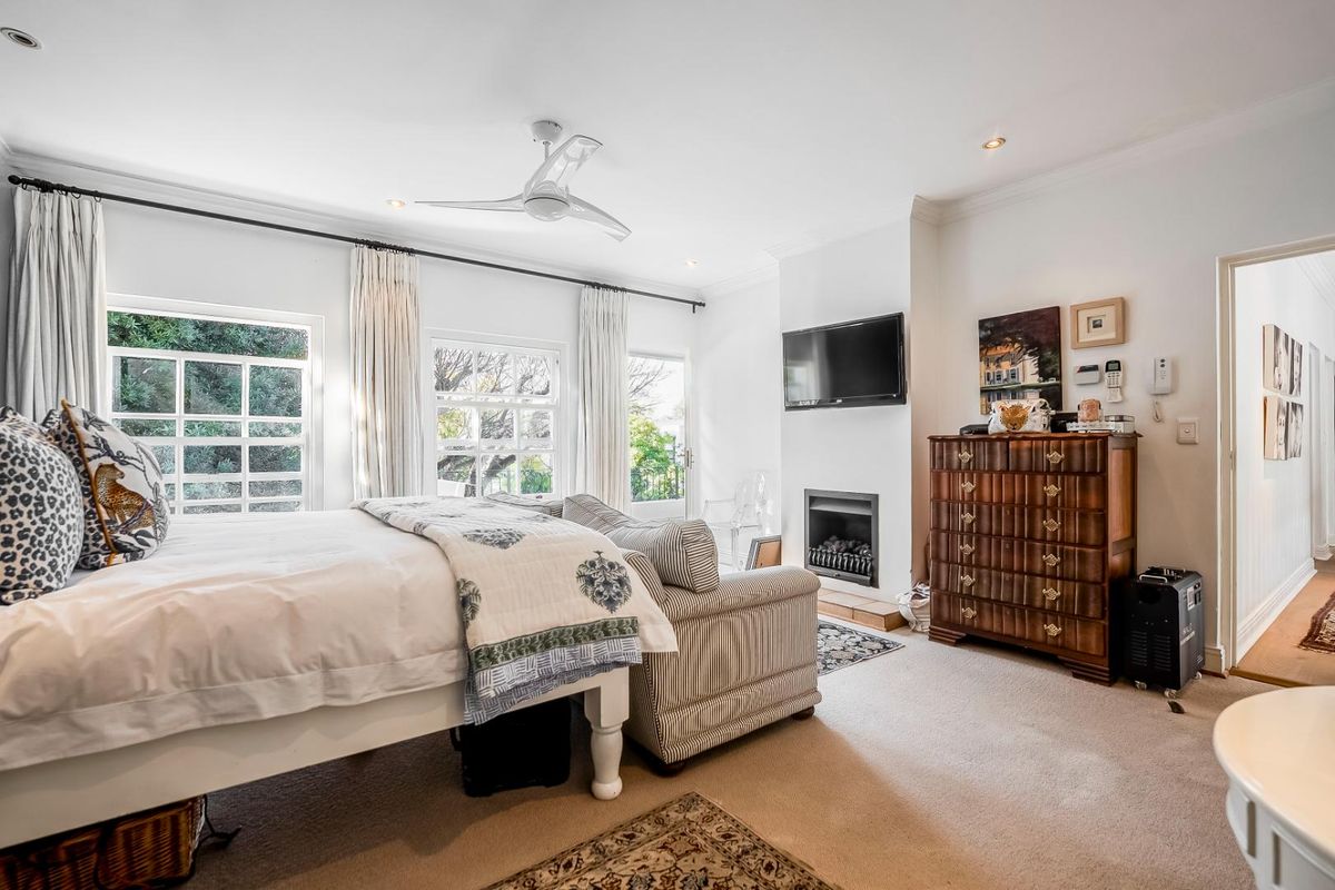 A well-maintained bedroom featuring a built-in fireplace, ceiling fan, and large windows that provide ample natural light.