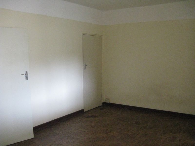 An empty bedroom featuring original parquet flooring and neutral wall finishes, offering a blank canvas for renovation or interior design updates.