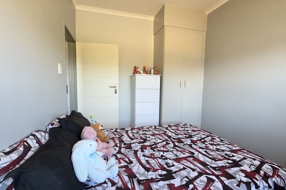 A well-maintained bedroom featuring neutral wall tones, a built-in wardrobe, and clean finishes, providing a comfortable and functional living space.