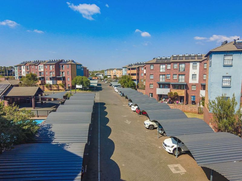 Aerial view of an apartment complex featuring multiple brick buildings, extensive covered parking bays, and solar panel installations on rooftops.
