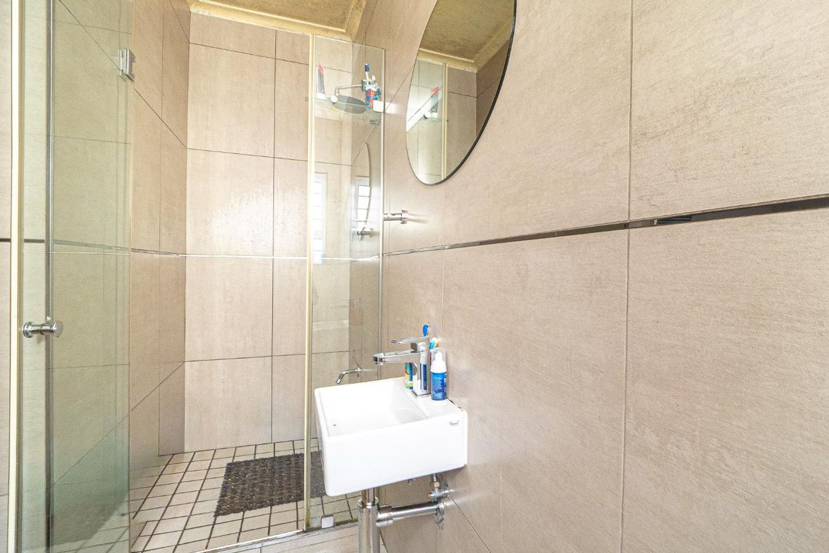 Modern bathroom featuring a wall-mounted basin, chrome fixtures, and a glass-enclosed shower with large format wall tiles.