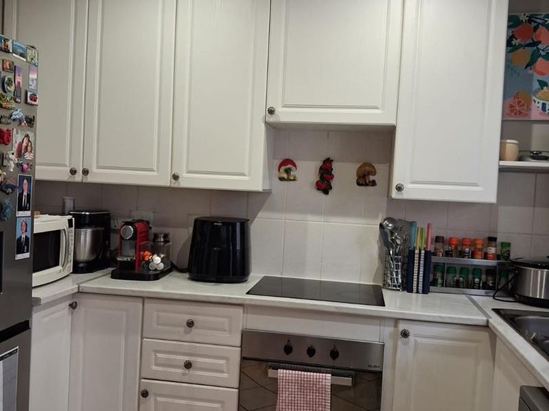 A functional kitchen featuring white cabinetry, a built-in oven, an electric hob, and tiled flooring with recessed lighting.