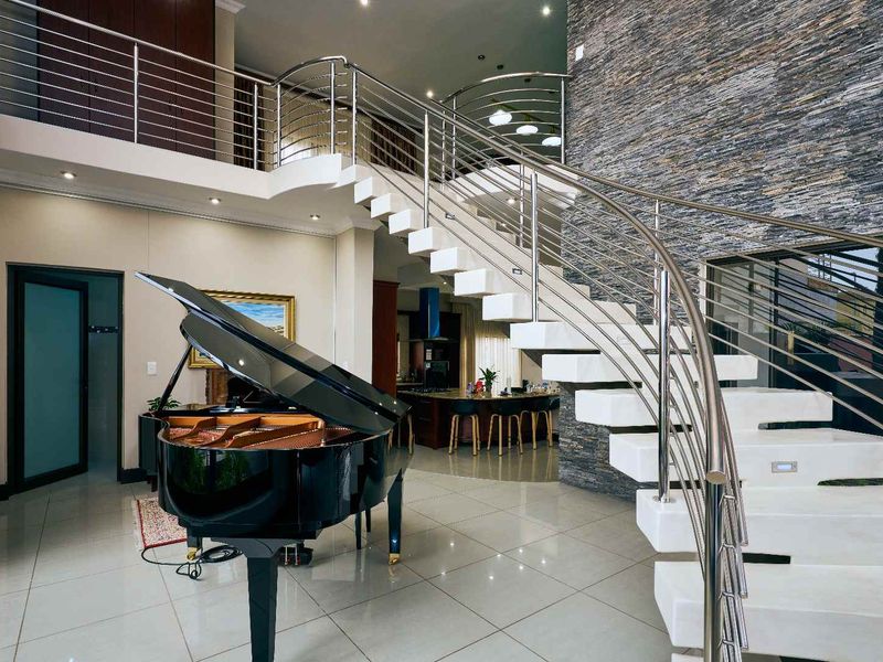 Spacious open-plan living area featuring a striking floating staircase with stainless steel balustrades and a dramatic stone feature wall.
