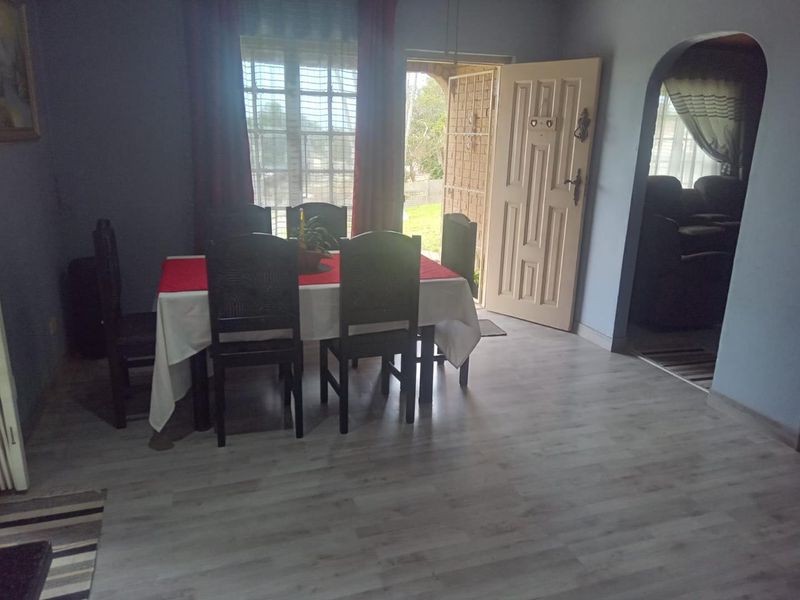 Dining area featuring light-toned laminate flooring, an arched entryway, and direct access to the exterior through a secure entrance door.