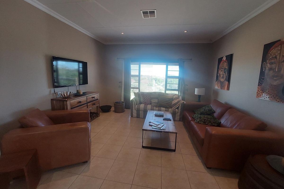 A spacious living room featuring tiled flooring, recessed ceiling lighting, and large windows that provide natural light.