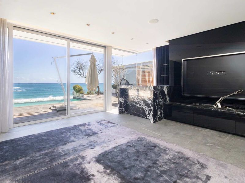 Modern living room featuring large sliding glass doors with ocean views, stone flooring, and a striking marble feature wall with built-in cabinetry.