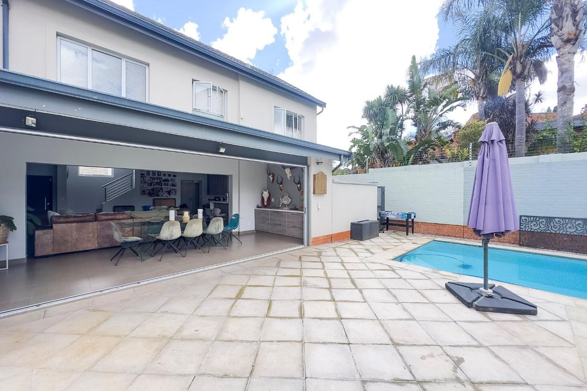 Spacious outdoor patio area featuring large sliding doors, tiled flooring, and a private swimming pool, perfect for seamless indoor-outdoor entertaining.