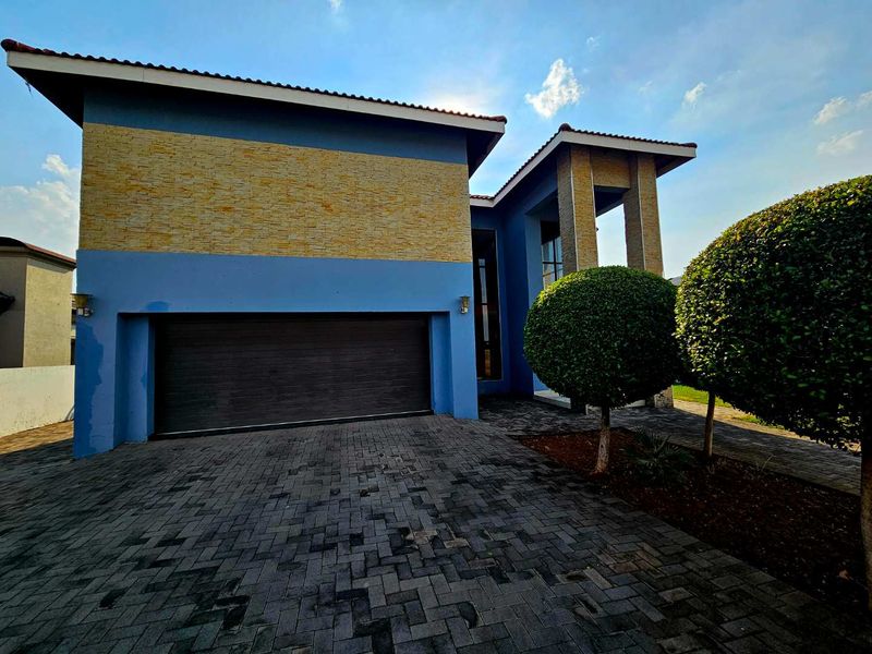 Front elevation of a modern house featuring a double garage, stone cladding accents, and a paved driveway.