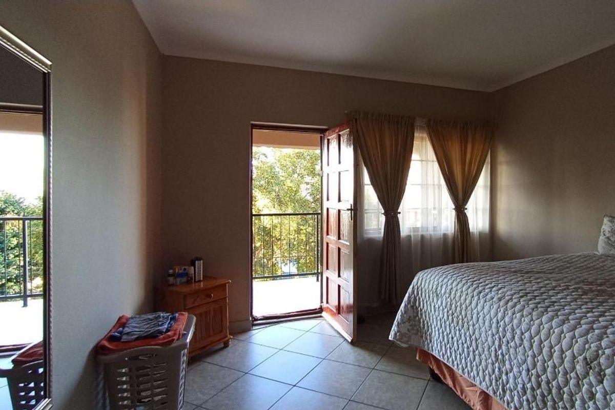 A bedroom featuring tiled flooring and direct access to a private balcony through a wooden door.