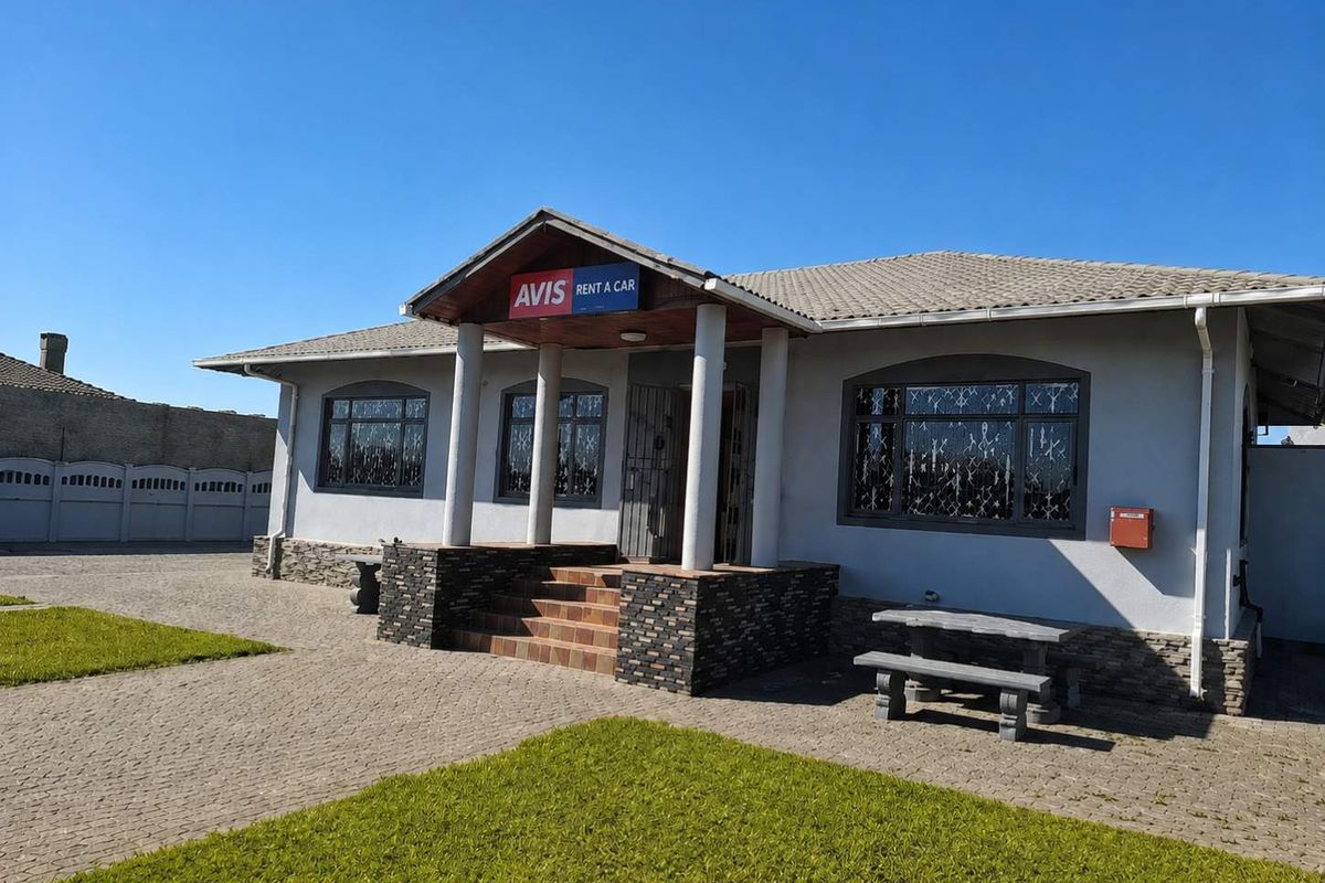 Front exterior view of a commercial property featuring a covered entrance porch, stone cladding accents, and paved driveway area.