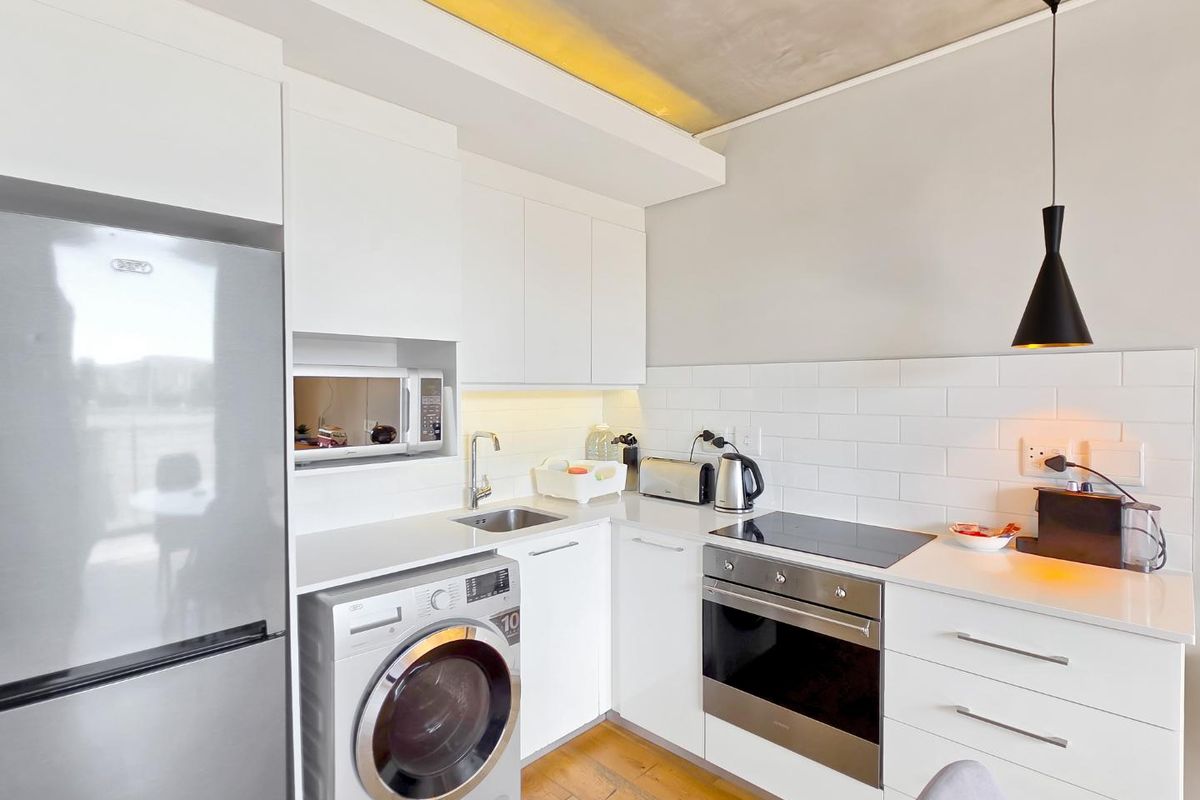 Modern kitchen featuring white cabinetry, subway tile backsplash, integrated appliances, and sleek finishes, offering a clean and functional culinary space.