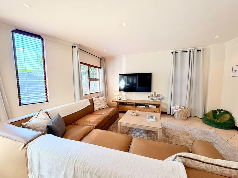 A bright and well-maintained living room featuring tiled flooring, recessed downlighting, and neutral wall finishes.