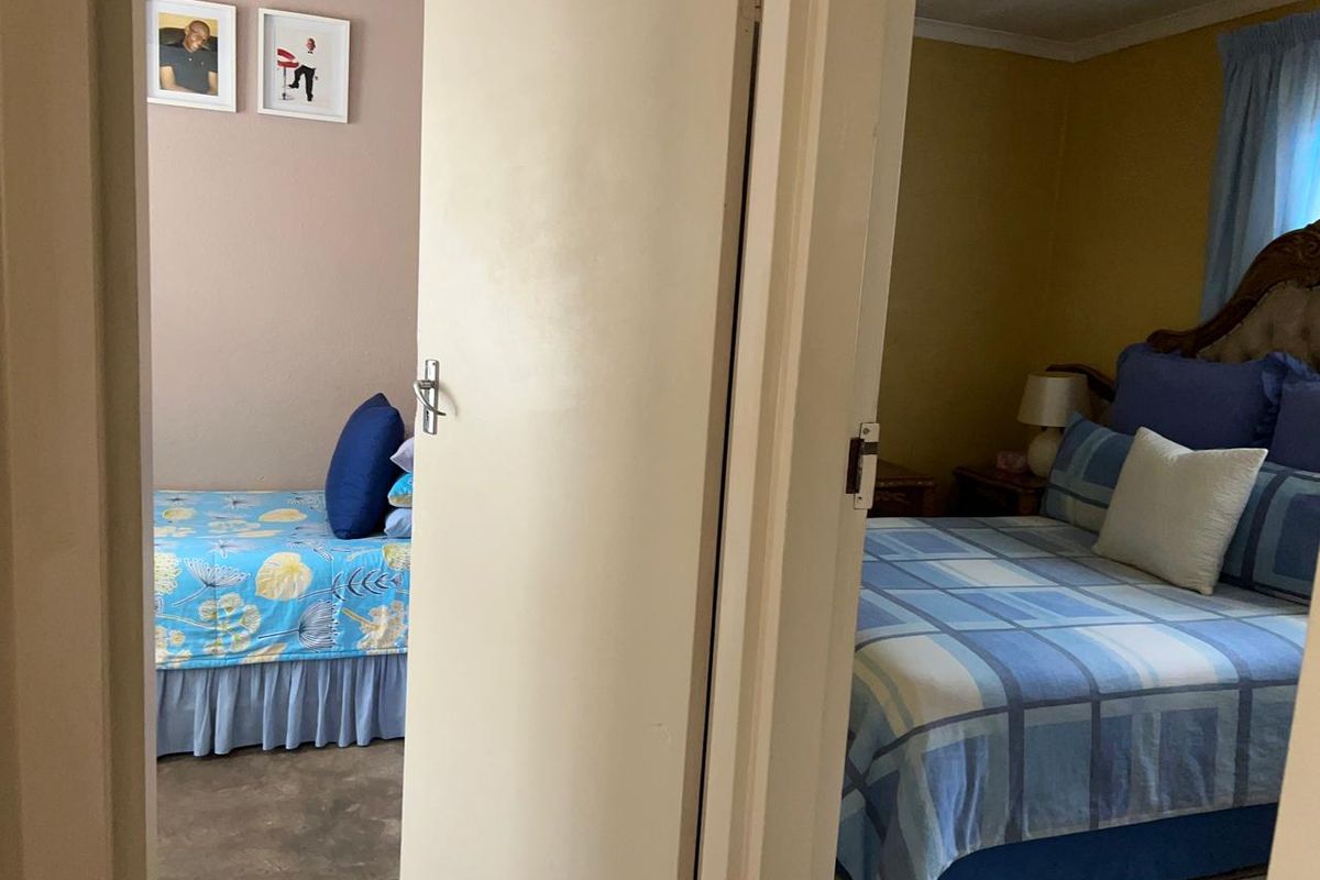 A view through a doorway showing two separate bedroom spaces with tiled flooring and neutral wall finishes.
