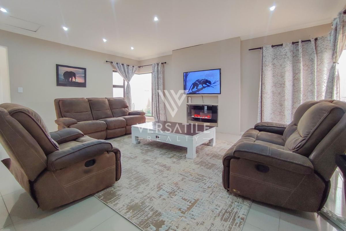 Spacious living room featuring tiled flooring, recessed downlights, and a modern built-in electric fireplace, creating a comfortable and inviting atmosphere.