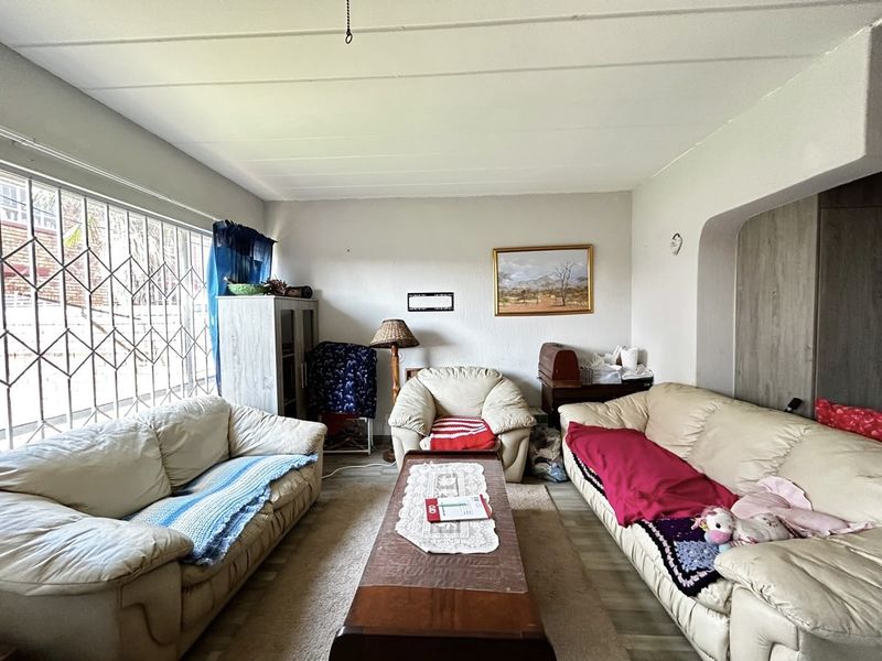 A living room featuring laminate flooring, a large window with security bars, and a decorative archway leading to an adjacent space.