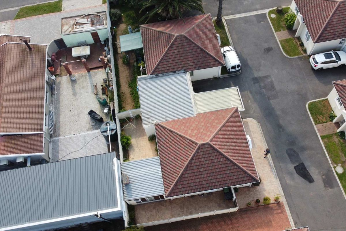 Aerial view of the property showing the roof structure, paved driveway, and surrounding residential layout.