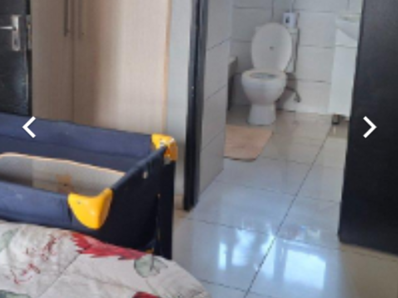 Bedroom featuring built-in cupboards and tiled flooring, with an open doorway leading to an en-suite bathroom.
