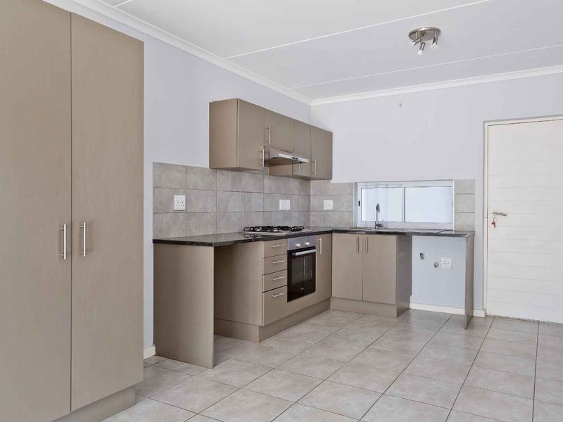 A clean, modern kitchen featuring neutral-toned cabinetry, granite countertops, a gas hob, and an integrated oven, offering a functional and well-maintained workspace.