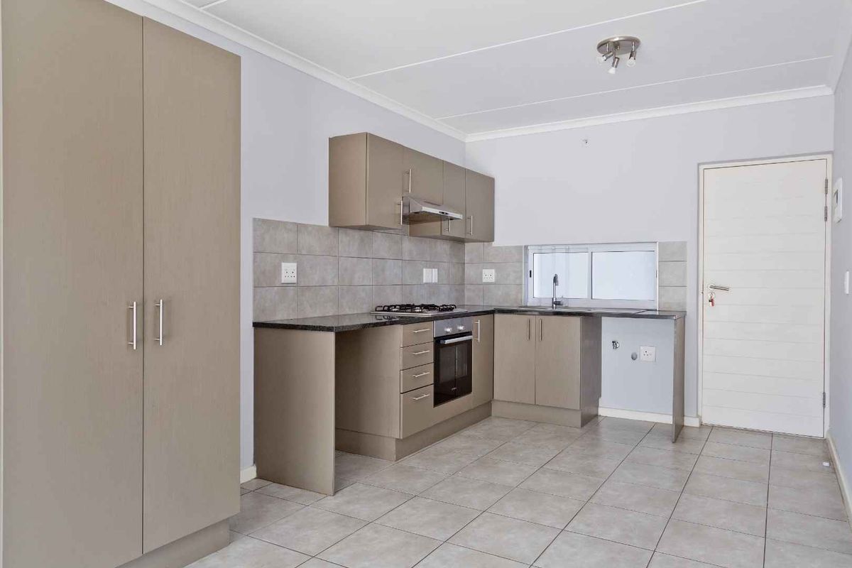 A clean, modern kitchen featuring neutral-toned cabinetry, granite countertops, a gas hob, and an integrated oven, offering a functional and well-maintained workspace.