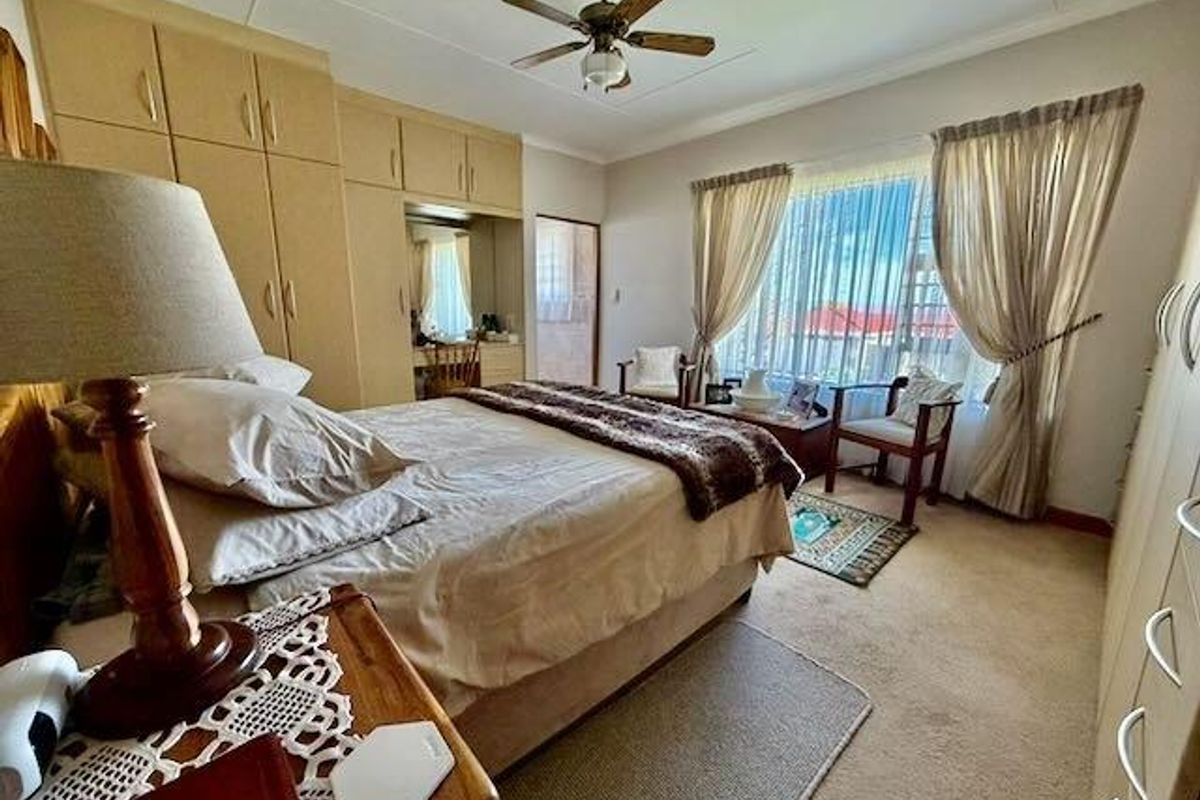 Spacious bedroom featuring extensive built-in cabinetry, a ceiling fan, and large windows with curtains, providing ample storage and natural light.