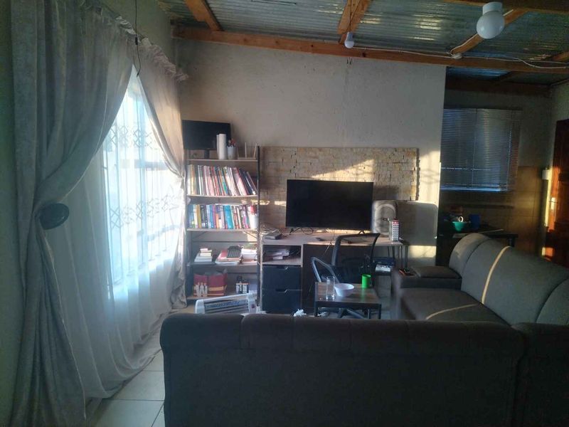 Living room featuring a stone veneer accent wall, tiled flooring, and an exposed corrugated metal ceiling structure.