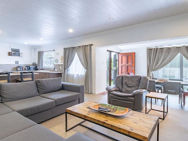 Spacious open-plan living area featuring a modern kitchen with island, timber-look ceiling, and seamless flow to the outdoor patio through sliding glass doors.
