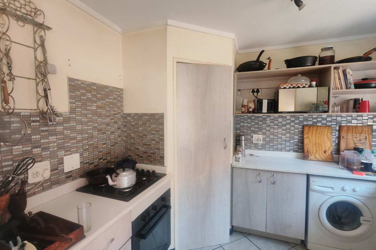 Compact kitchen featuring a gas hob, built-in oven, mosaic tile backsplash, and functional laminate cabinetry with integrated laundry appliance space.