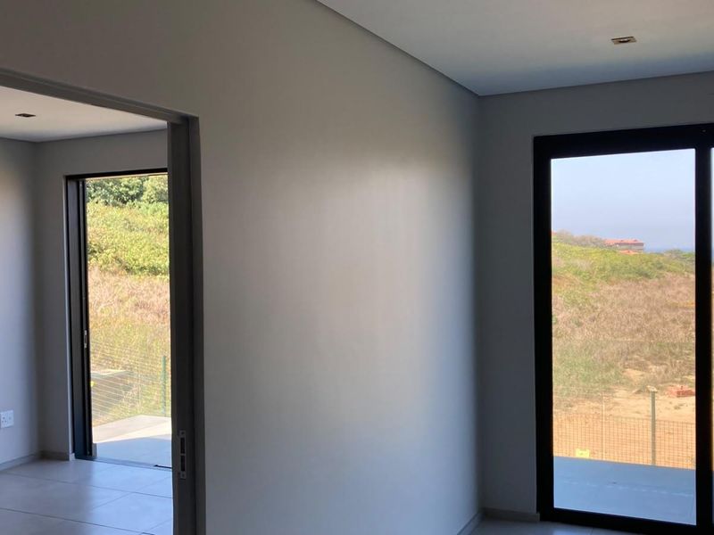 A bright, modern, and empty bedroom featuring large sliding glass doors that provide natural light and access to an outdoor area.