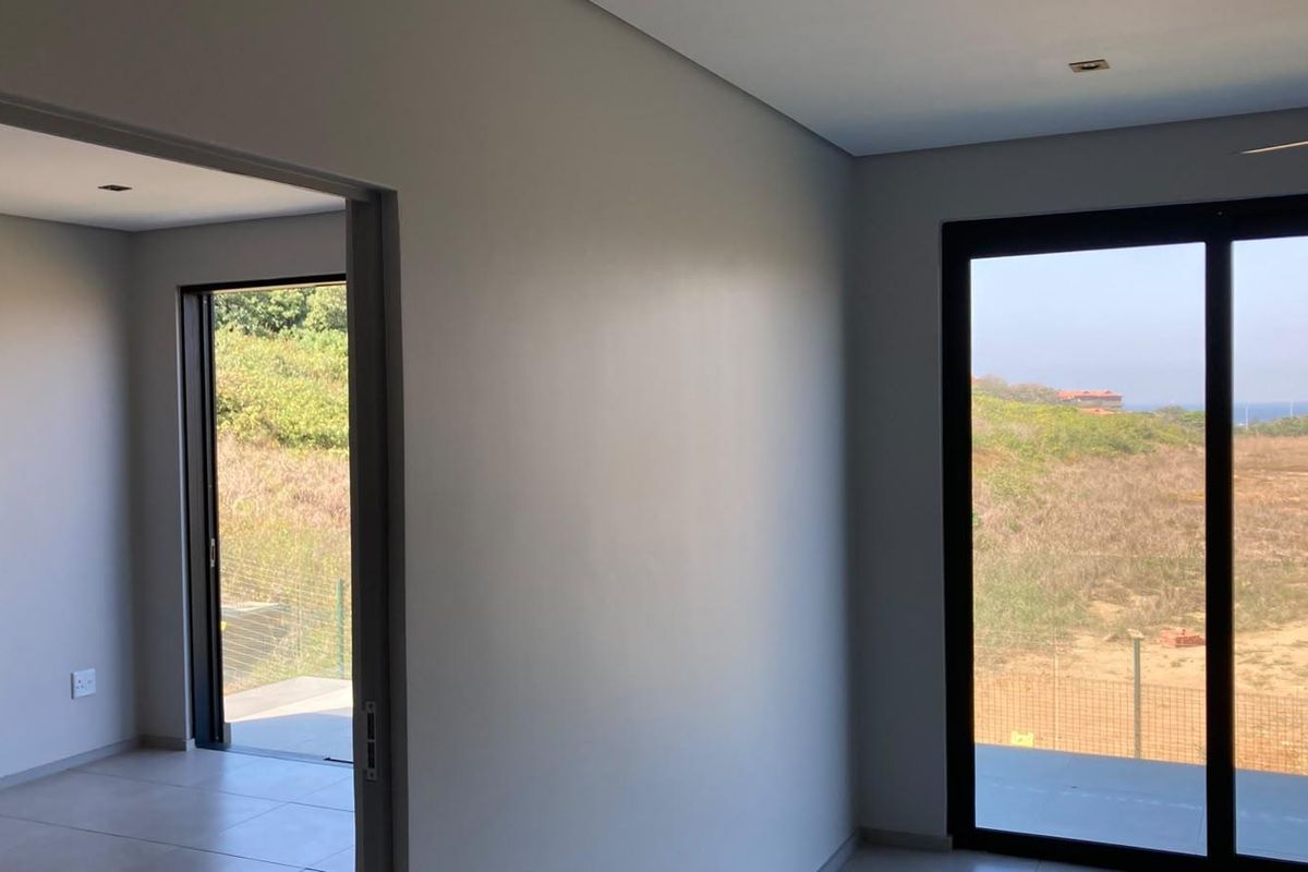 A bright, modern, and empty bedroom featuring large sliding glass doors that provide natural light and access to an outdoor area.