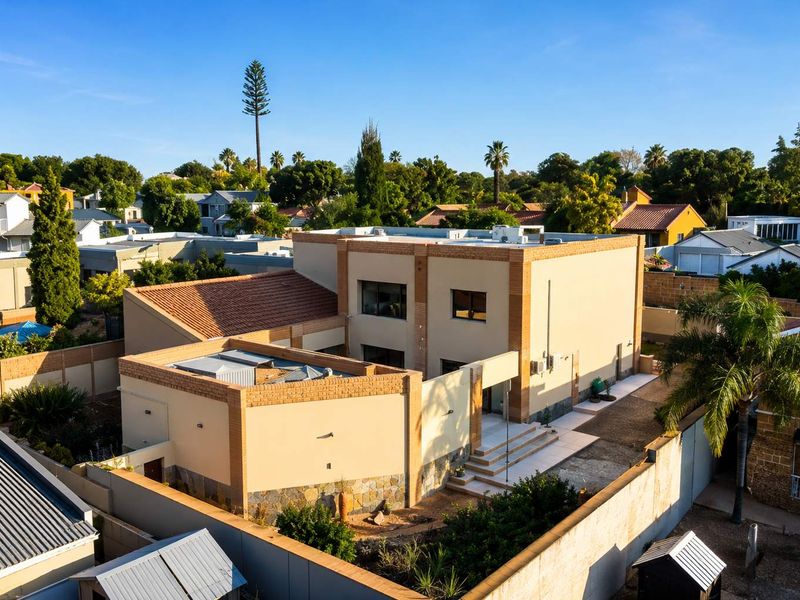 Aerial view of a modern two-story residential property featuring a combination of brick and rendered finishes, tiled roofing, and secure boundary walls.