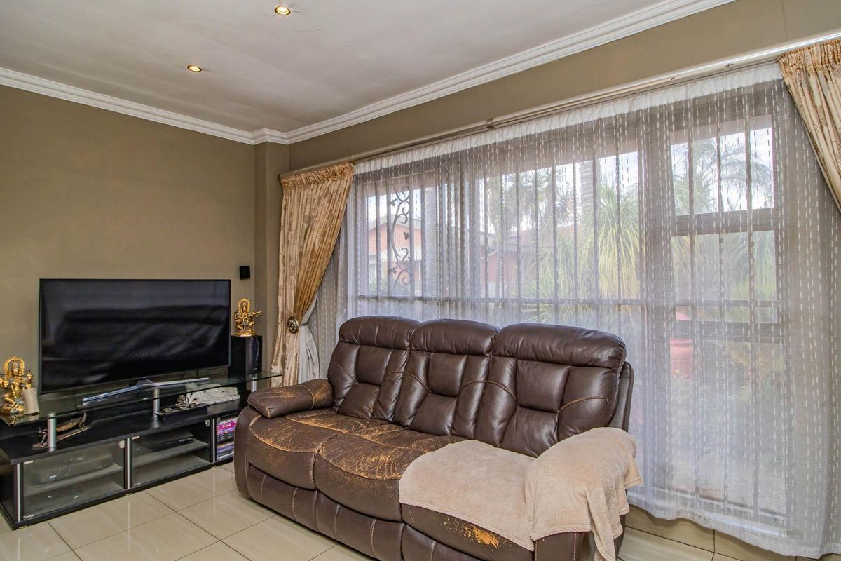 A comfortable living room featuring large windows with natural light, tiled flooring, and recessed ceiling lighting.