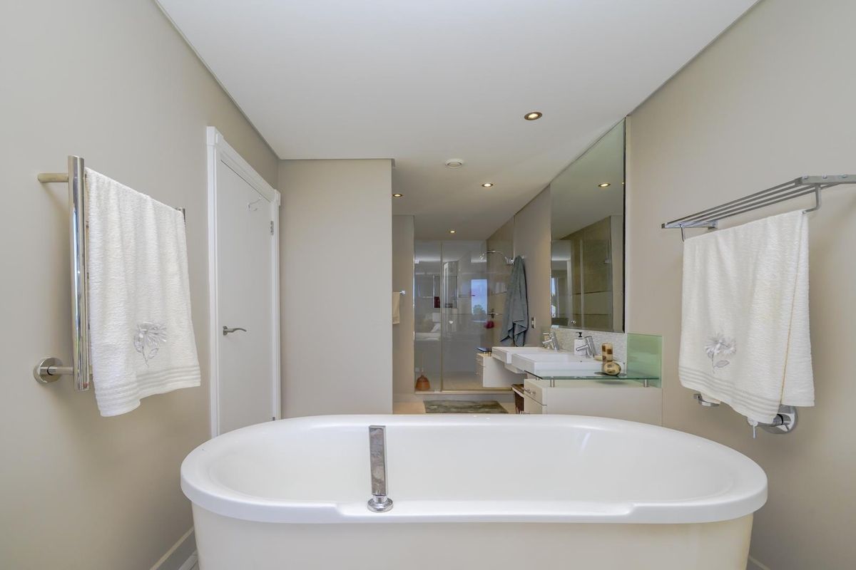 Modern bathroom featuring a sleek freestanding bathtub, double vanity with large mirror, and a separate glass-enclosed shower area with recessed lighting.