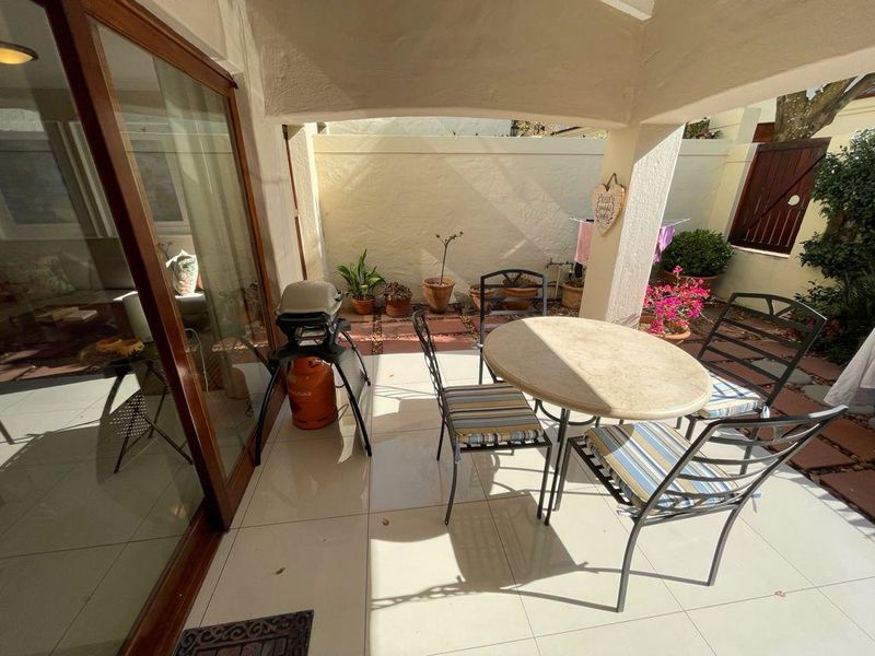 A covered patio area featuring tiled flooring and large sliding glass doors, providing a seamless transition to the outdoor space.
