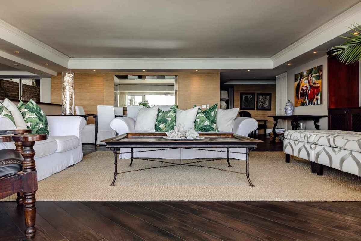 A spacious living room featuring dark hardwood flooring, textured wall finishes, and elegant cove ceiling detailing with recessed lighting.