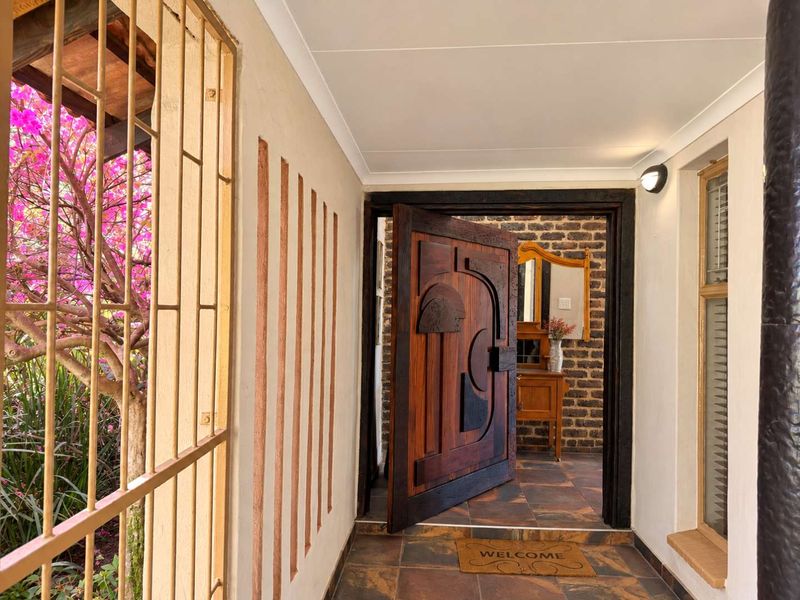 Welcoming entrance hall featuring a unique custom carved wooden door, exposed brick accents, and durable tiled flooring.