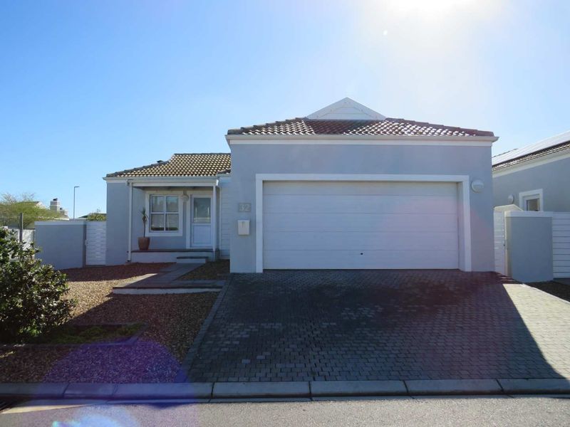 Front elevation of a single-story house featuring a paved driveway, double garage, and low-maintenance gravel garden.