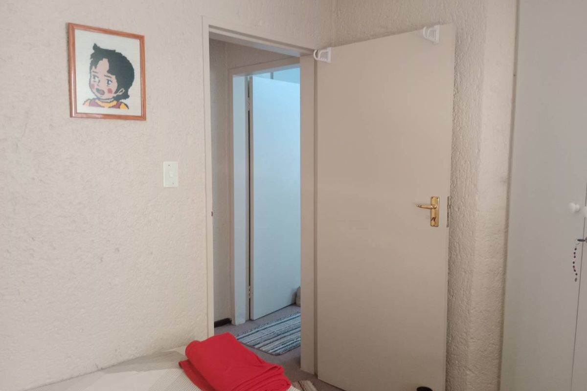 A view from a bedroom looking through an open doorway into a hallway, featuring textured wall finishes and built-in cupboard doors.