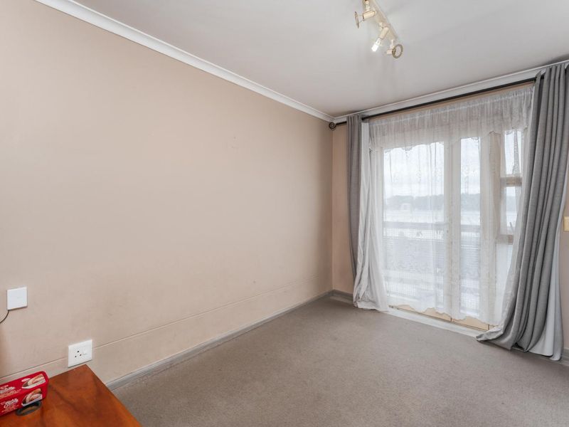 A bright, empty bedroom featuring neutral walls, carpeted flooring, and a sliding glass door providing access to an outdoor area.