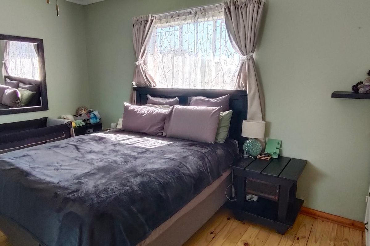 A bedroom featuring timber flooring and neutral wall tones, providing a functional space with natural light.