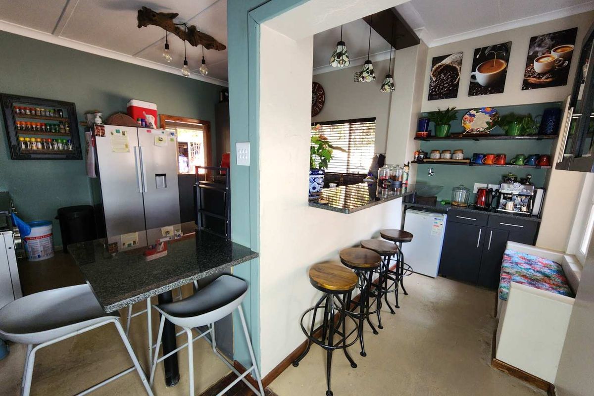 A functional kitchen area featuring granite countertops, a breakfast bar with seating, and built-in cabinetry with open shelving for storage.