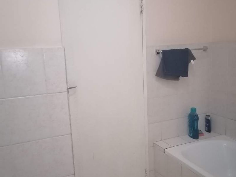 A functional bathroom featuring a built-in bathtub, tiled walls, and tiled flooring, providing a clean and practical space.