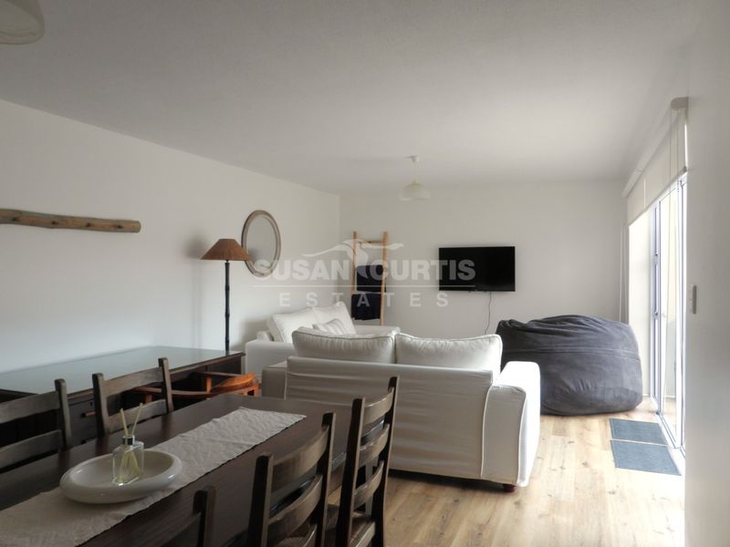 Open plan living and dining area featuring light laminate flooring and large sliding glass doors providing access to the exterior.