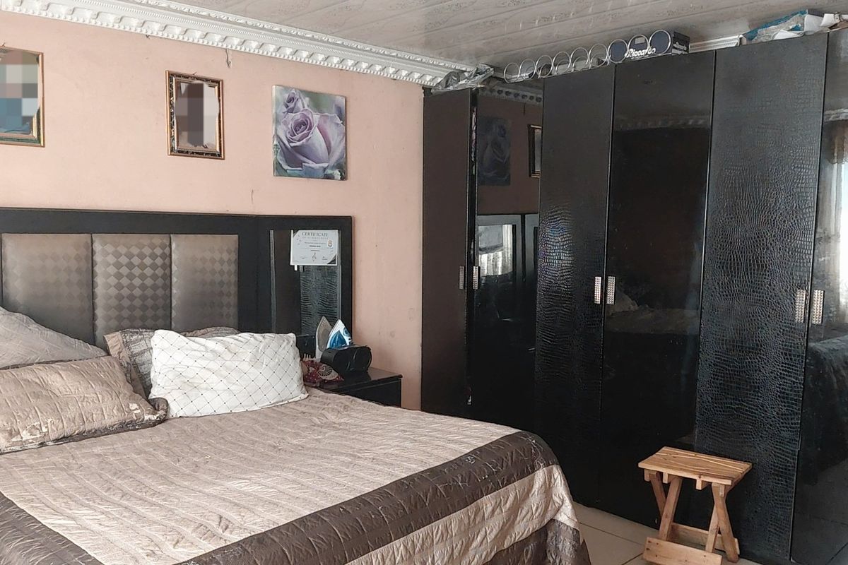 A bedroom featuring a built-in wardrobe and decorative ceiling cornice, requiring cosmetic updates to the wall and ceiling finishes.