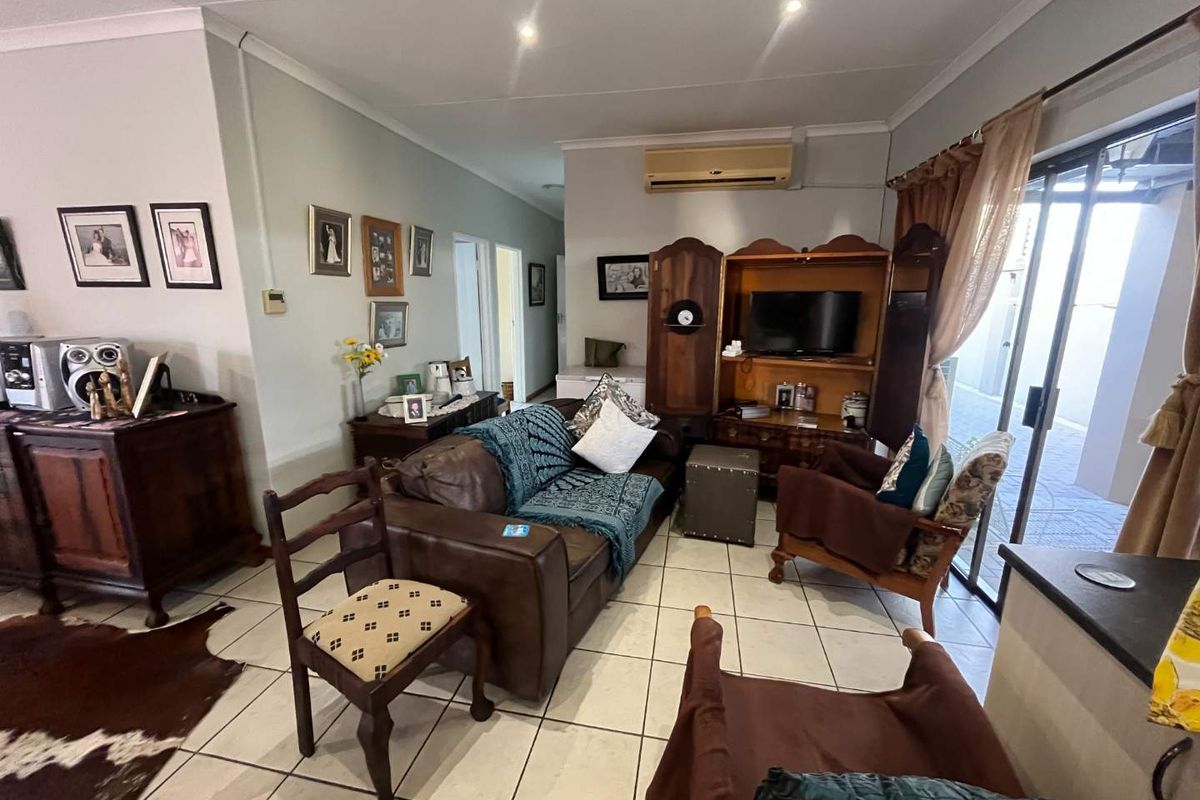 A living room featuring tiled flooring, recessed ceiling lighting, and sliding glass doors providing access to the outdoor area.