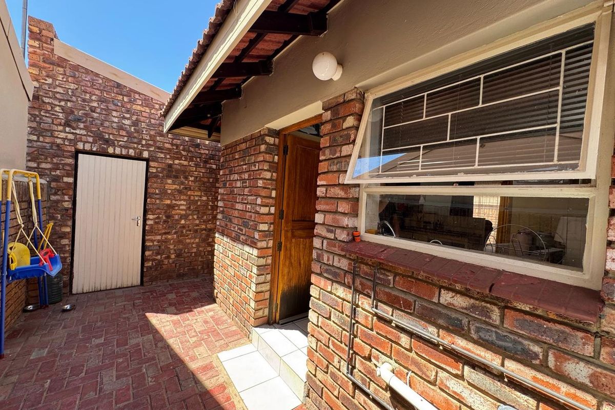 A private rear courtyard featuring exposed brick walls, paved flooring, and direct access to the home through a wooden door.